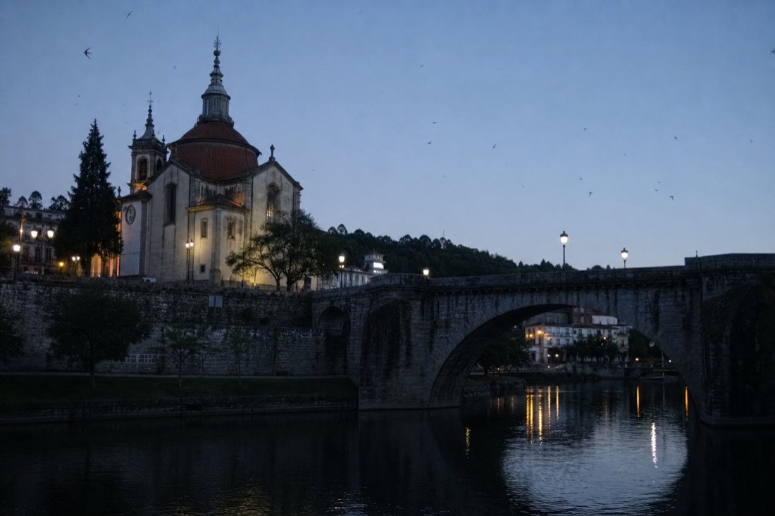 Evening light on the Tamega river in Amarante with the bridge and church silhouetted and lamps reflecting on the water