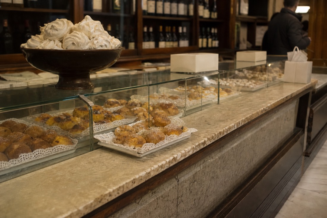 Glass bakery counter in Amarante displaying rows of traditional sugared pastries on paper doilies