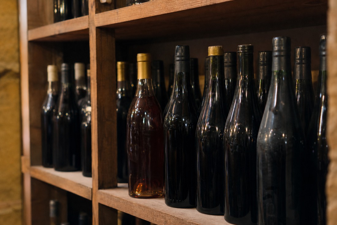 Shelf of assorted unlabeled port bottles in a shop lit by warm lamplight