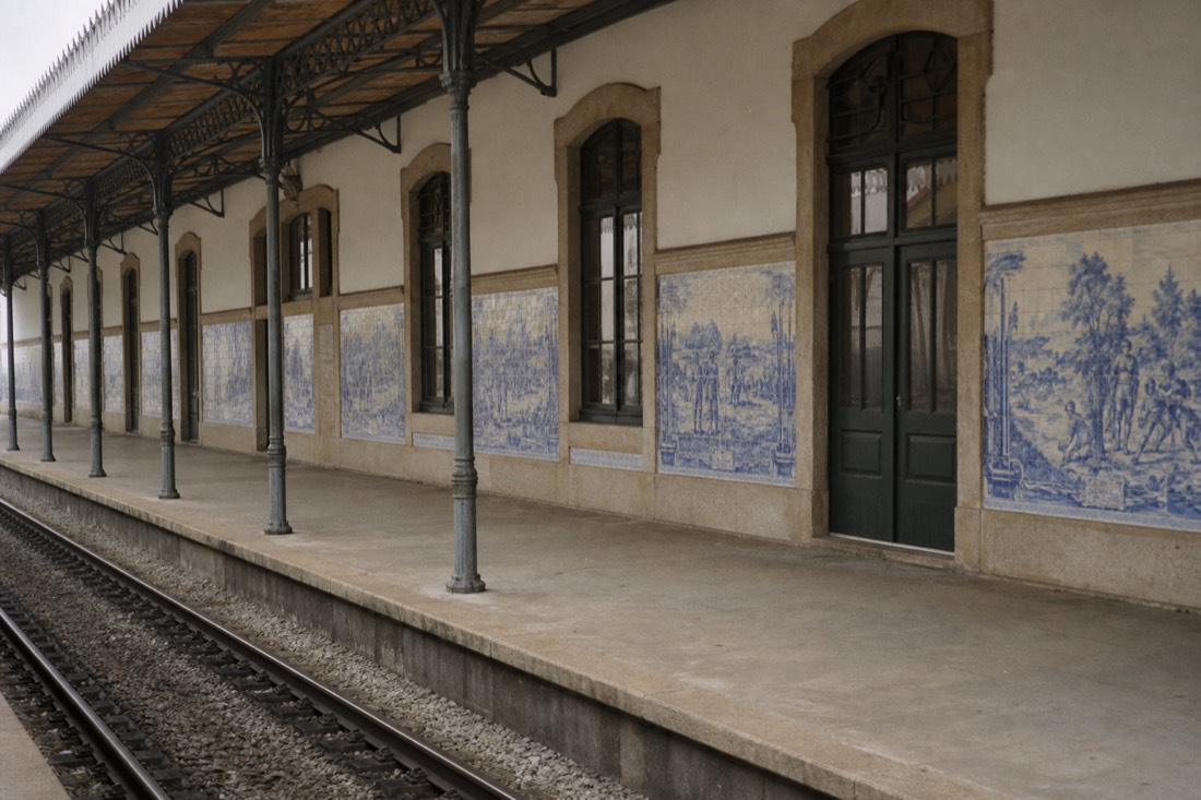Historic railway station building with blue and white tile panels along its platform wall