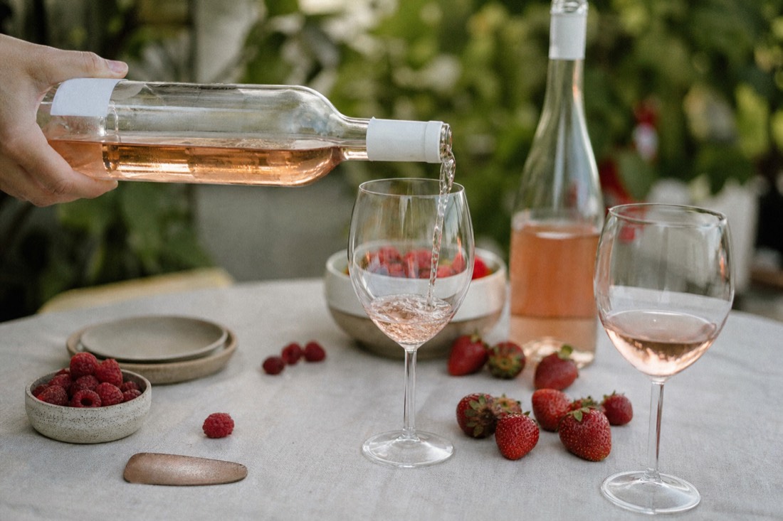Pale pink port poured into a chilled glass beside fresh berries on a bright outdoor table