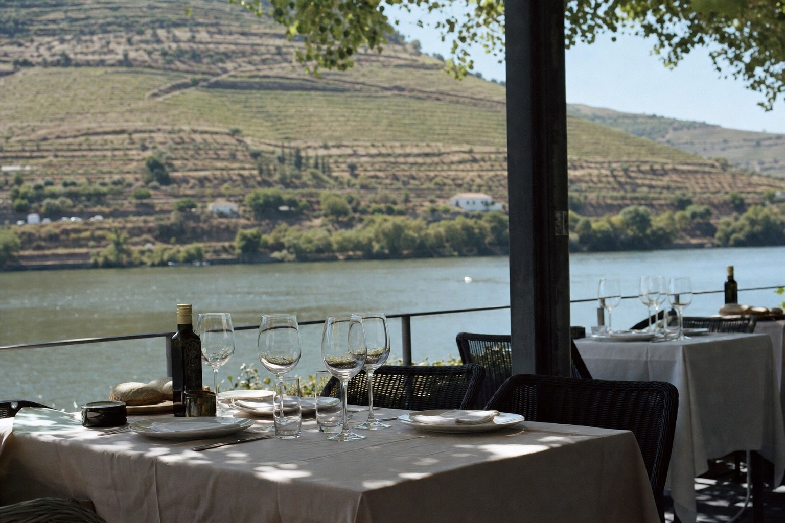 Outdoor restaurant terrace set for lunch overlooking the Douro river and terraced vineyards in warm light