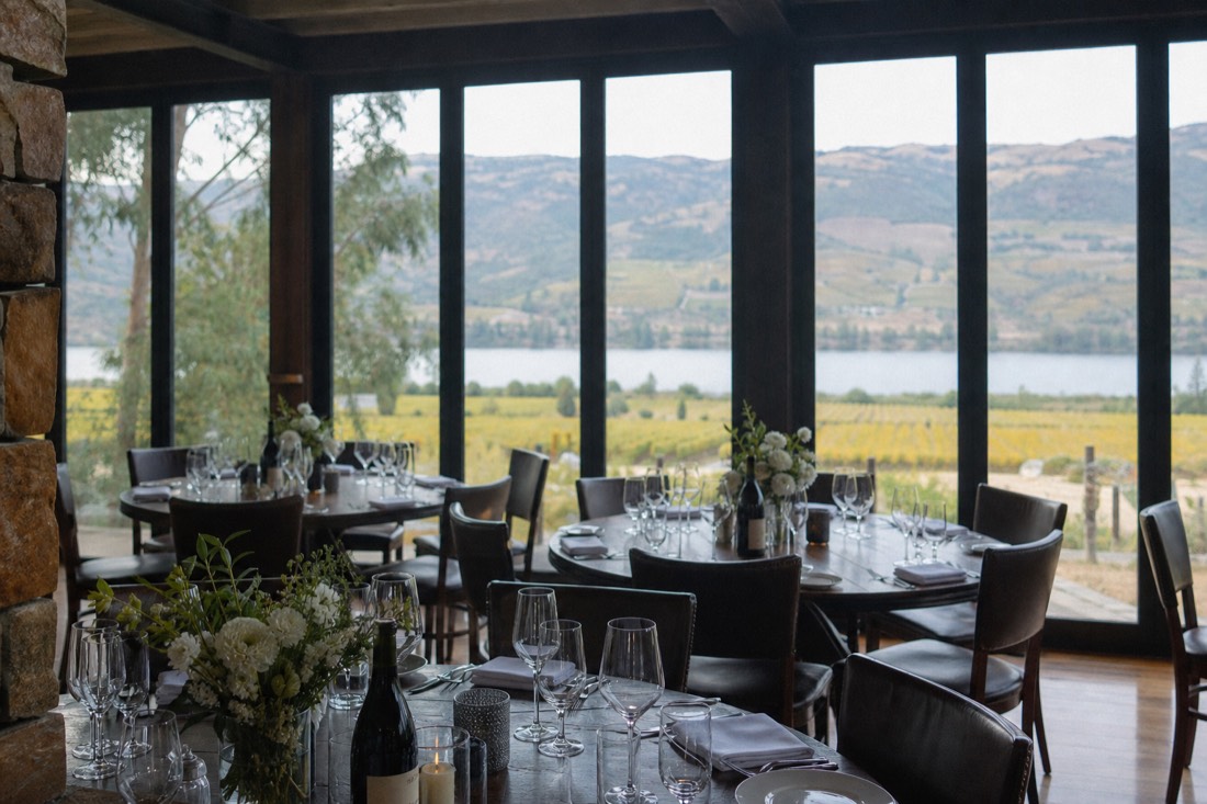 Elegant winery dining room with floor to ceiling windows looking out over vineyards and the river