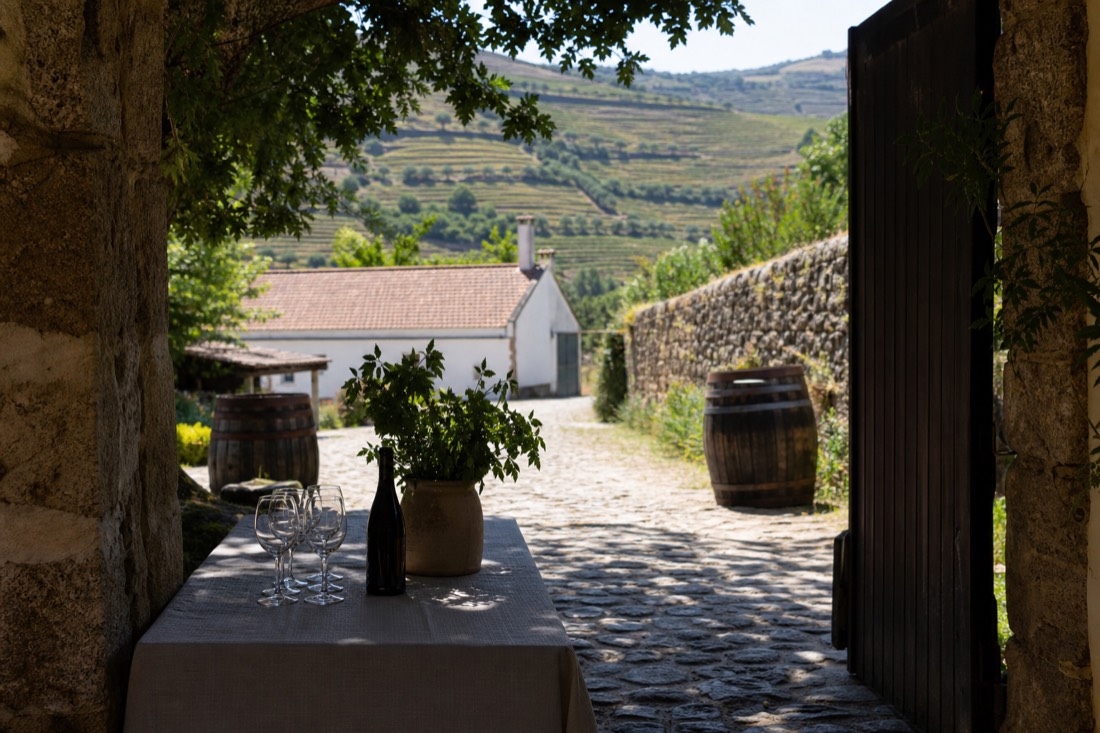 A stone quinta gateway and courtyard in the Douro Valley with barrels and tasting glasses set out