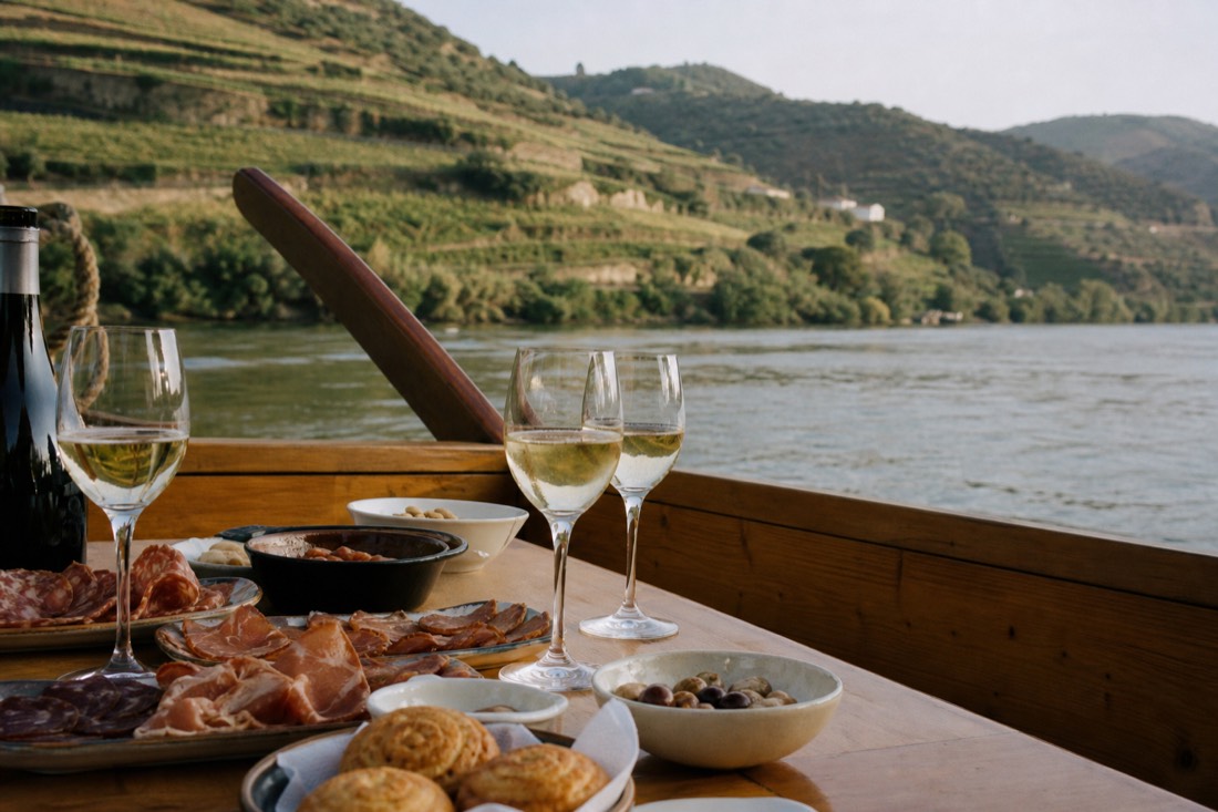 Wooden boat deck on the Douro River set with regional tapas, pastries and sparkling wine glasses