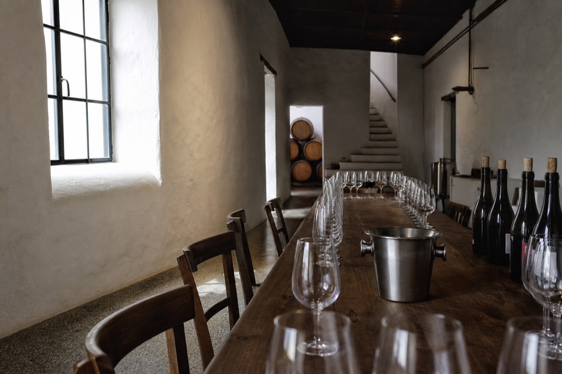 Empty tasting room table set with glasses and a spittoon, morning light through a quinta window