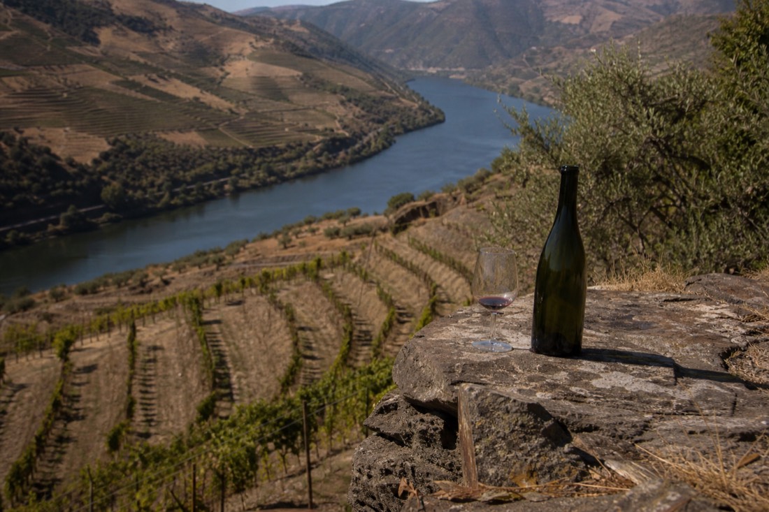 Hazy midsummer afternoon over sun-baked Douro terraces, heat shimmering above the schist slopes