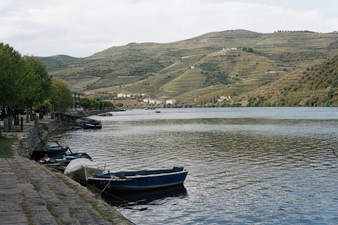 Boats and a riverside promenade at Pinhão with terraced hills rising behind, an alternative to the full day trip