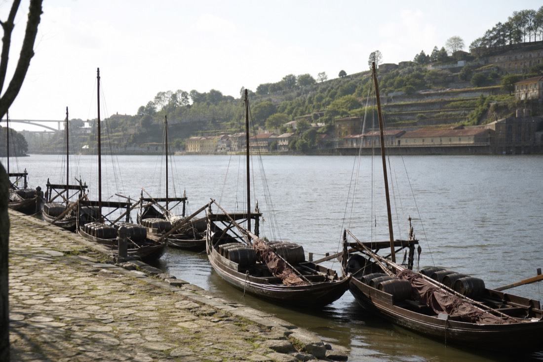 Wooden rabelo boats moored in a row at a quay, the boats behind three very different cruise products