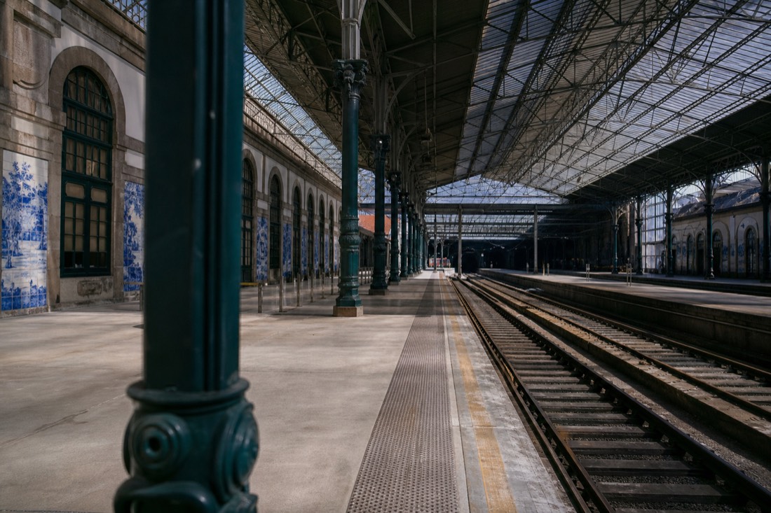 Railway platform under the arched glass roof of a Portuguese station at midday