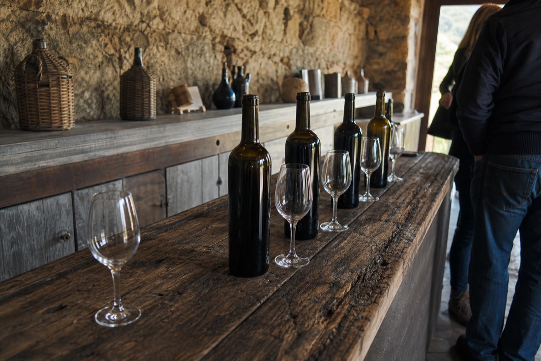 Weathered price-free tasting counter with wine bottles and glasses in a Douro quinta shop