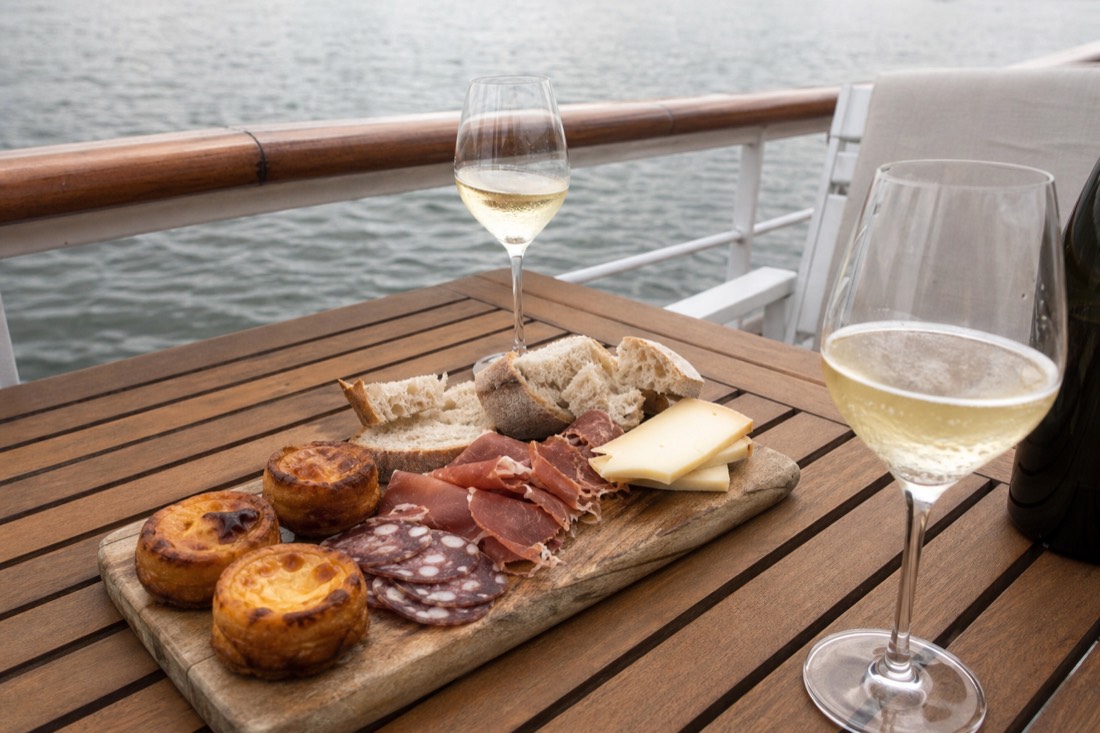 Tapas board with regional smoked meats, pastries and sparkling wine on a boat deck table