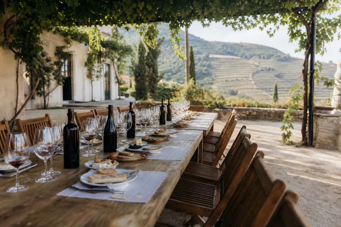 Small group seated at a long tasting table in a Douro estate courtyard with bottles and glasses