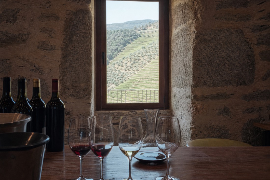 Stone tasting room of a Douro wine estate with glasses set out and vineyards through the window