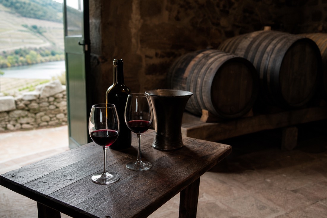Small tasting table with two glasses of port in a stone-walled Douro quinta cellar