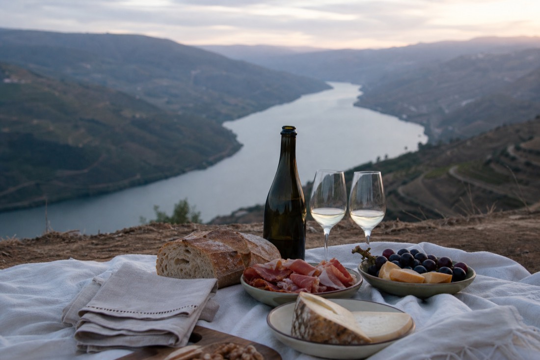 Freshly set picnic spread with sparkling wine, bread and regional food on a linen cloth overlooking the Douro