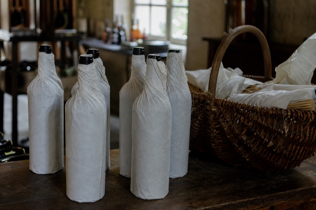 Unbranded bottles of Douro wine wrapped for travel beside a wicker basket in a quinta shop