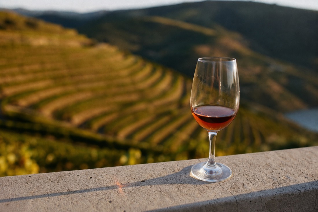 Glass of tawny Port catching the light on a terrace railing above Douro Valley vineyards