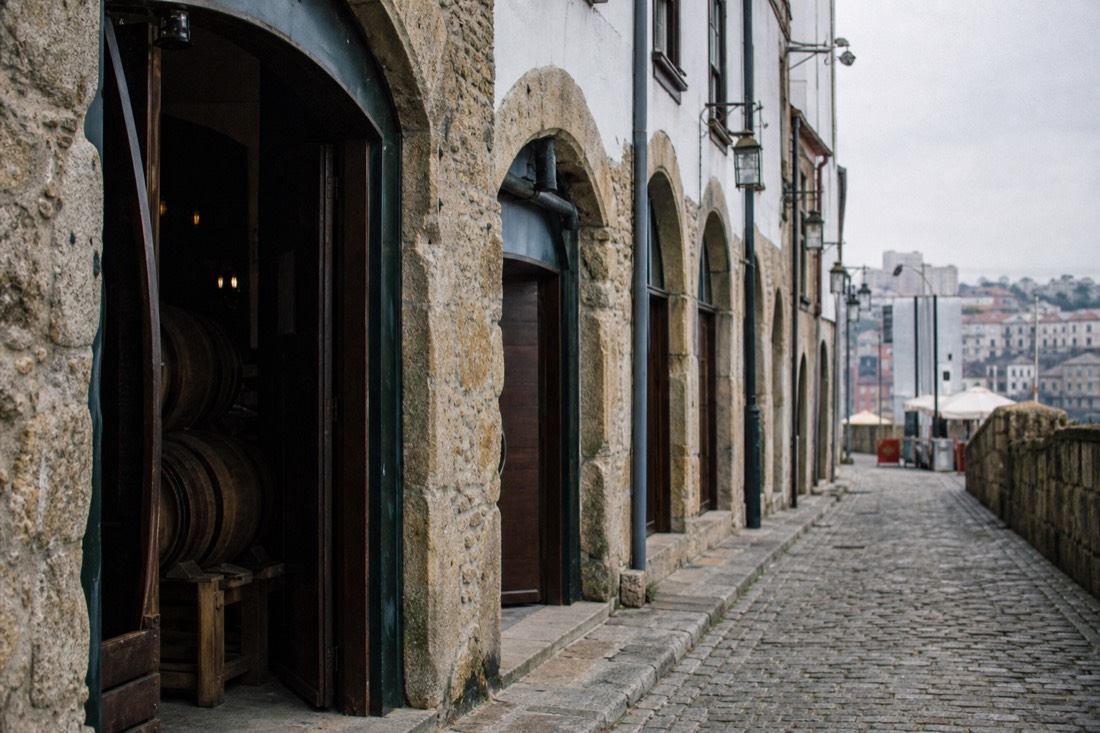 Narrow cobbled street in Gaia lined with the entrances of historic Port wine lodges