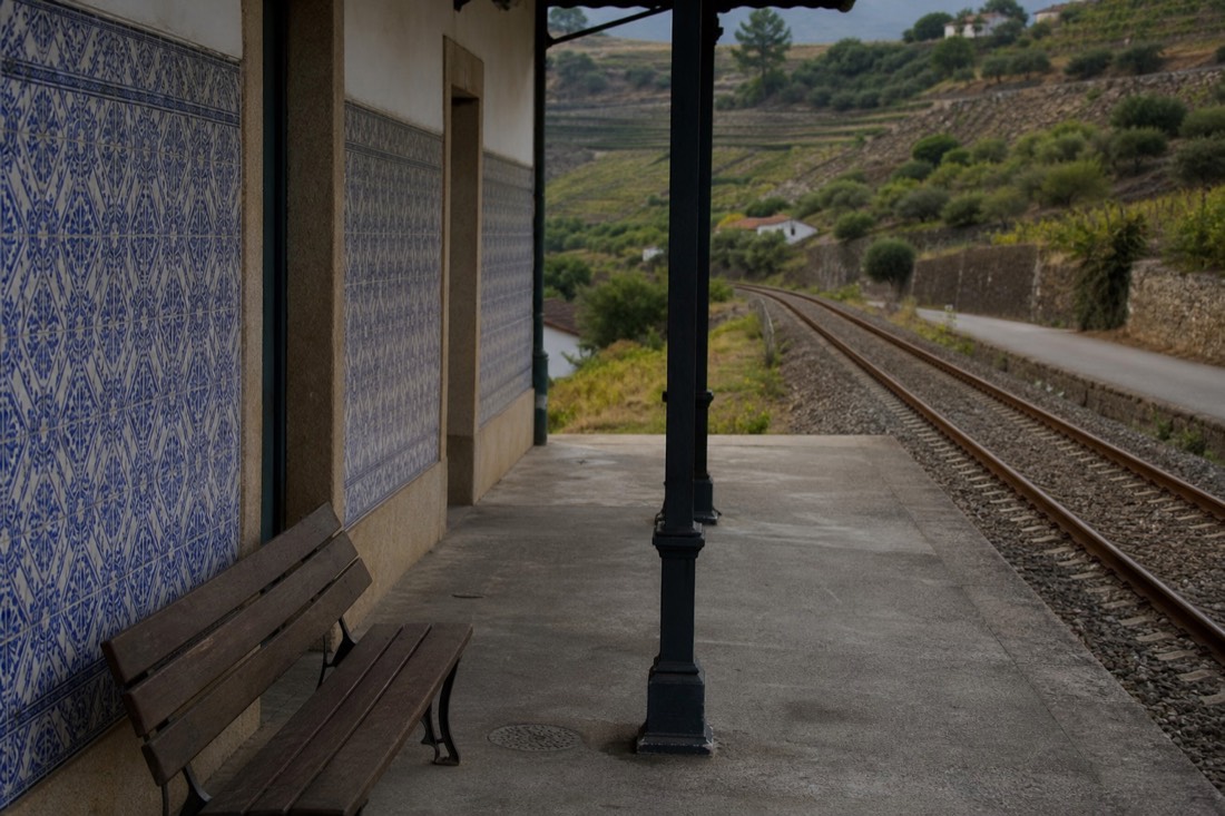 Azulejo-tiled railway station platform on the Douro line with vineyard hills rising behind
