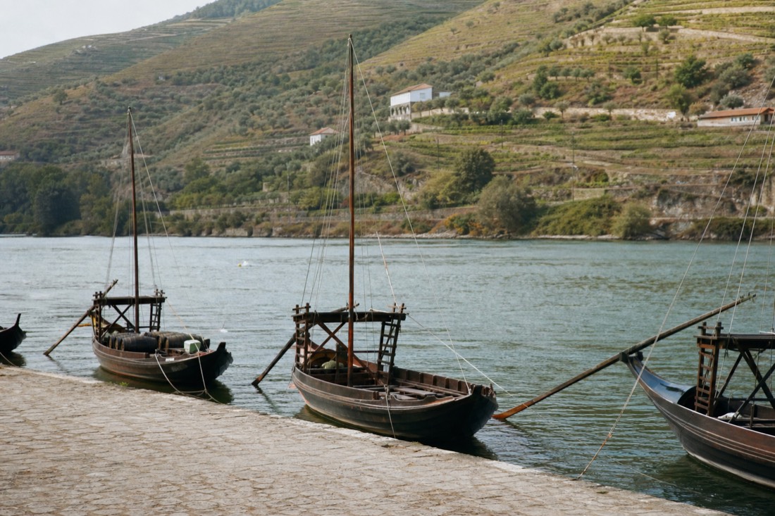 Quiet Pinhão riverside with moored boats and vineyard slopes a short walk from the station