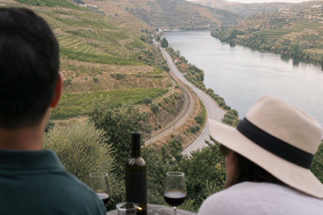 Road, rail line and river running side by side along the Douro Valley floor between vineyards