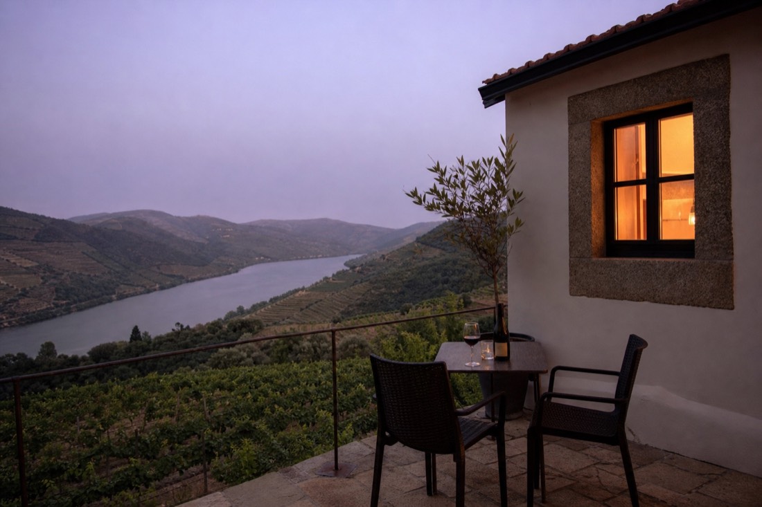 Quinta guesthouse terrace at dusk overlooking rows of vines dropping toward the Douro