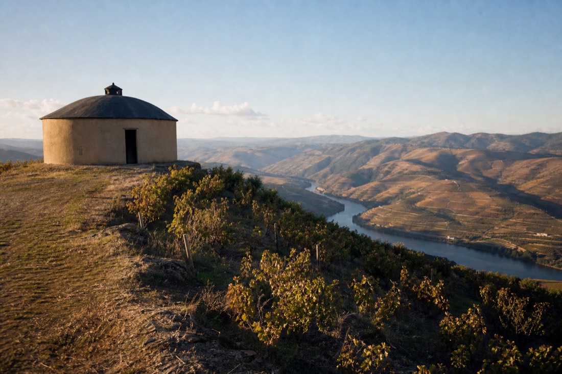 Round hilltop building on a vineyard ridge with a wide open view over the Douro valley below