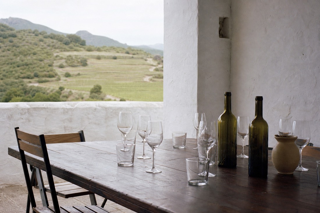 Empty tasting table set with glasses on a quiet estate terrace, morning light over the vineyards