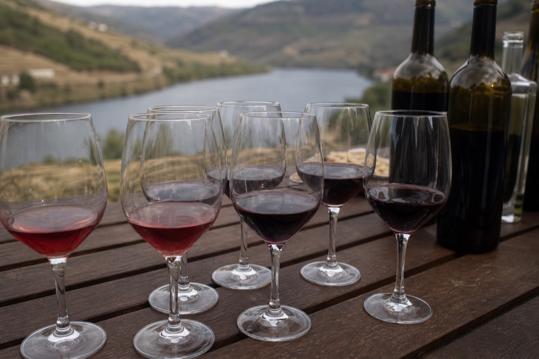 Tasting glasses of port and Douro wine set out on a terrace table above the river