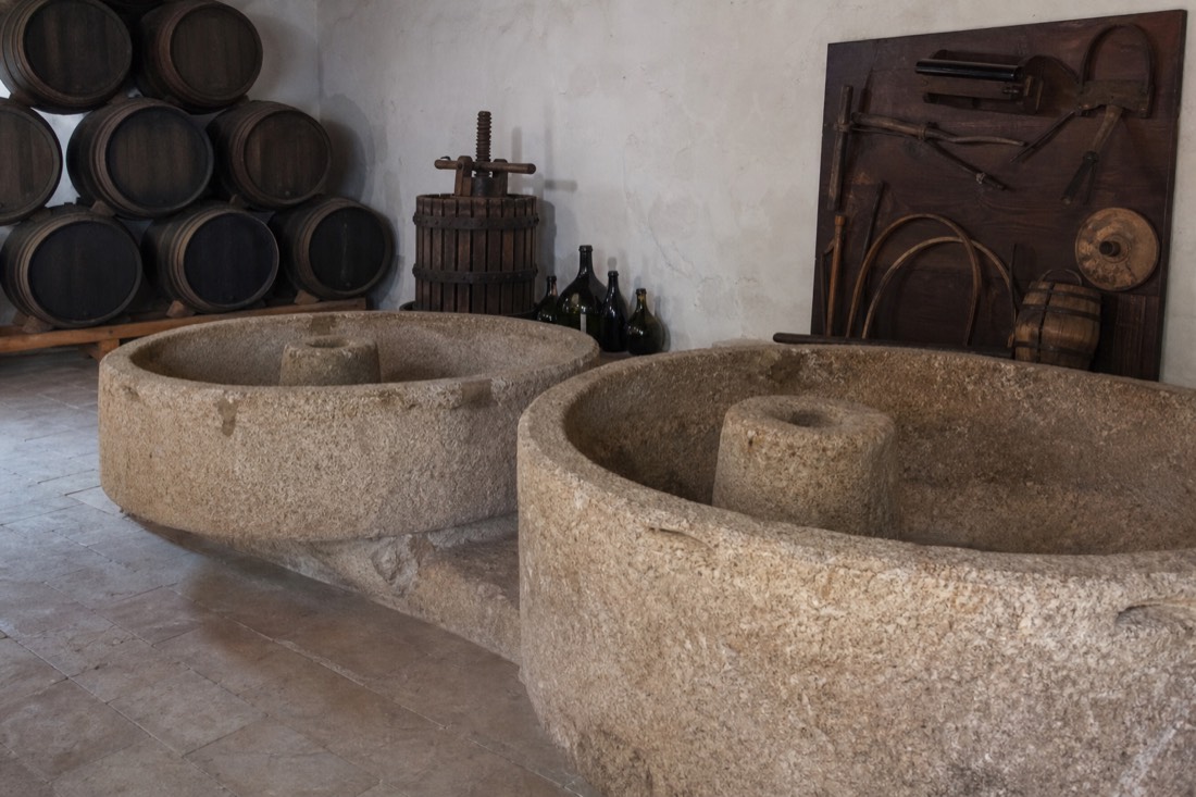 Old stone lagares and barrels inside a historic Douro wine lodge with a small museum display