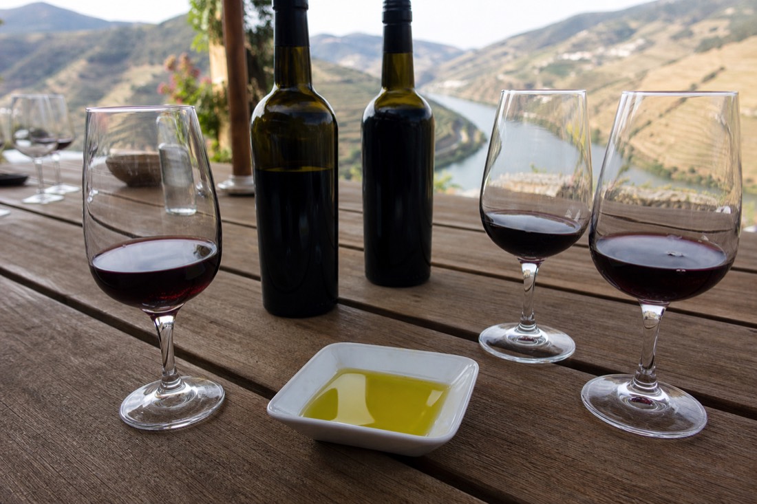 Tasting table with glasses of port and red wine and a dish of olive oil overlooking the river