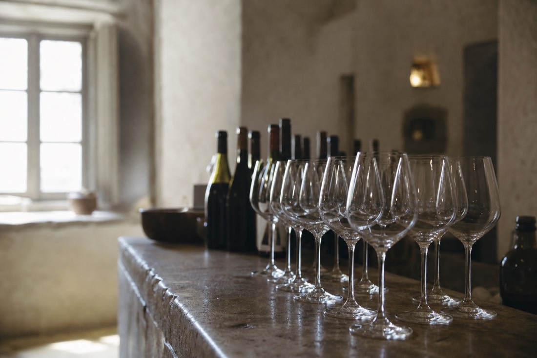 Row of wine glasses on a stone counter in a quiet estate tasting room with soft window light