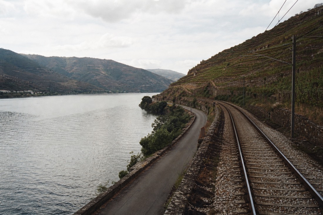 Railway line and river running side by side through a gorge lined with vineyard terraces